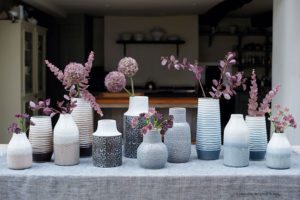 Composition of white and blue vases with purple flowers